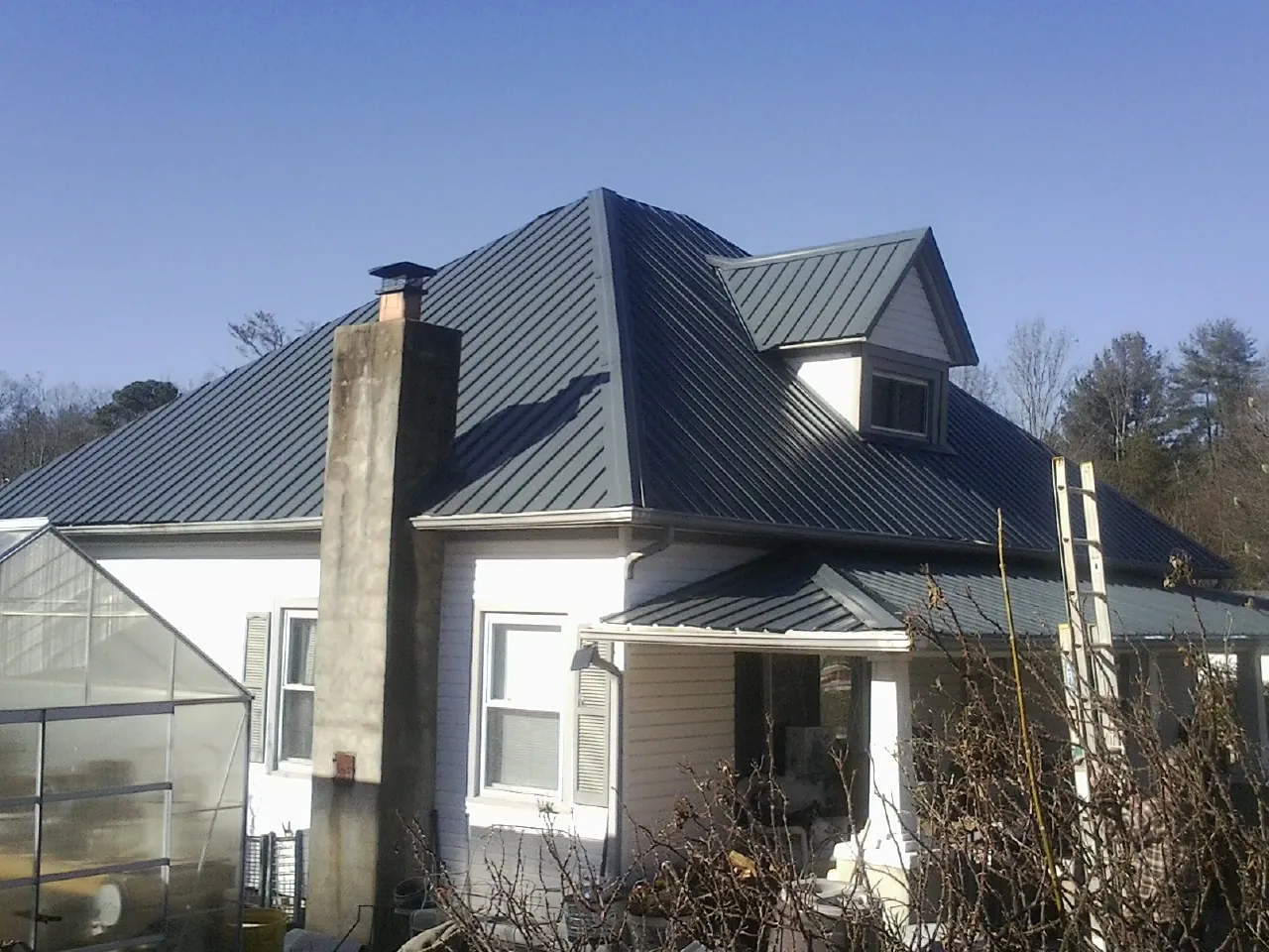 Dark blue standing seam metal roof on a white farmhouse with dormer — Slate & Tile Roof Repair by Roofing Brothers in Port Angeles