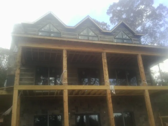 Dormers and porch framing on a large log home under construction — Roof Coating work by our crew in Port Angeles