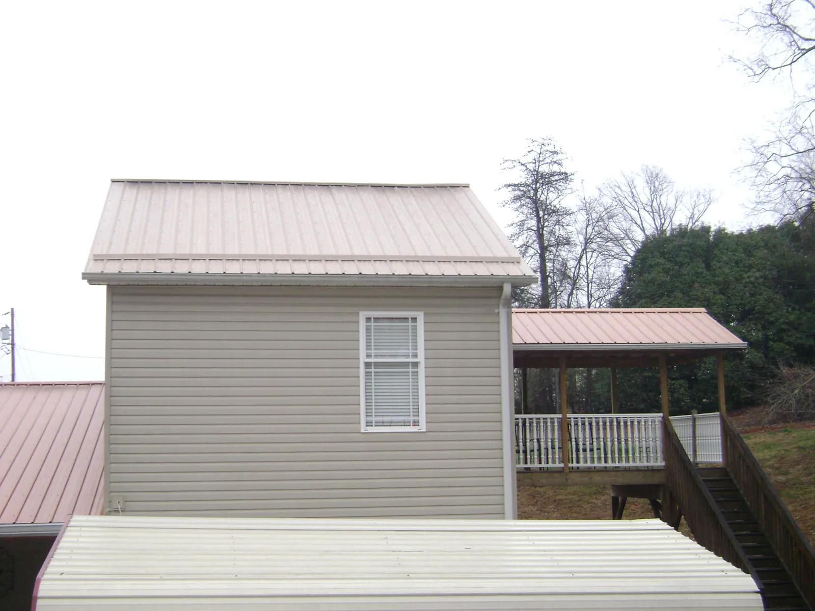 Tan metal roofs on a two story addition and attached porch, from a Roof Replacement job in Port Angeles