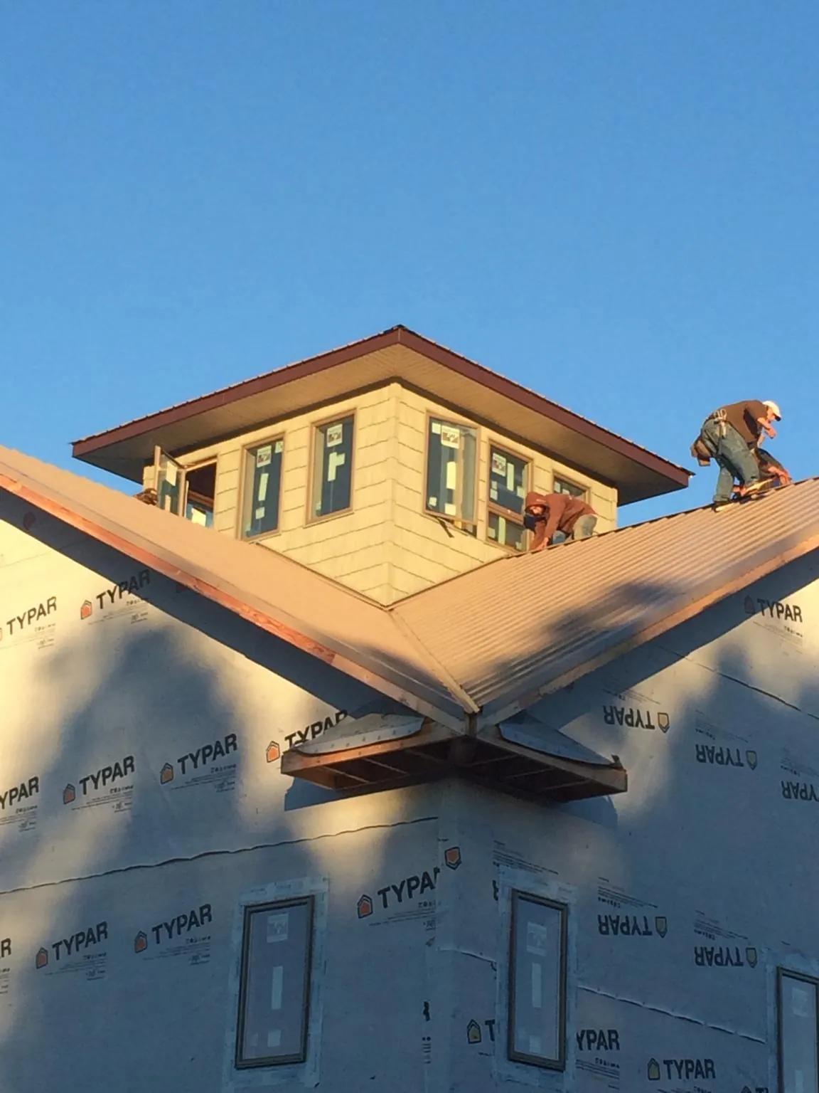 Roofers working around a rooftop cupola on a new metal roof at sunset — Roof Waterproofing in Port Angeles by Roofing Brothers